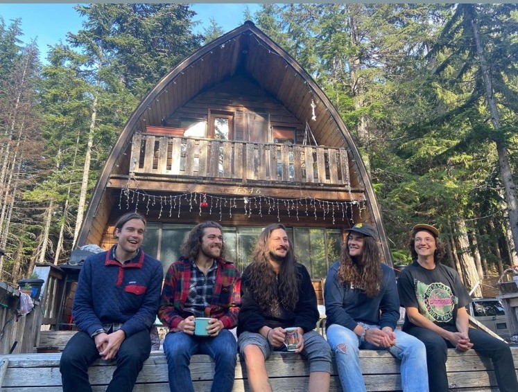 Lazy Ghost members sitting in front of a cabin